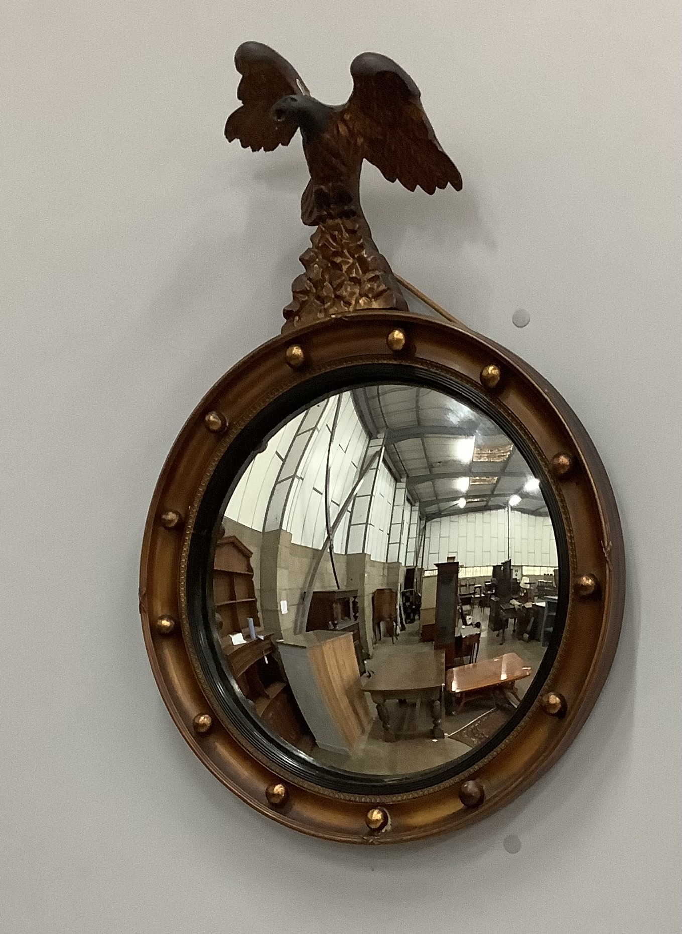 A Regency style convex circular wall mirror with eagle pediment, height 66cm